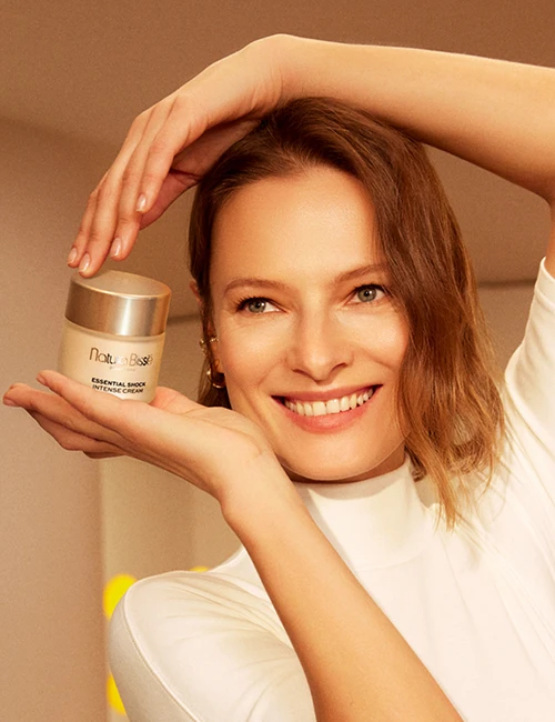 Smiling woman holds Essential Shock Intense in her hands above her head. Product featured in bestsellers page.
