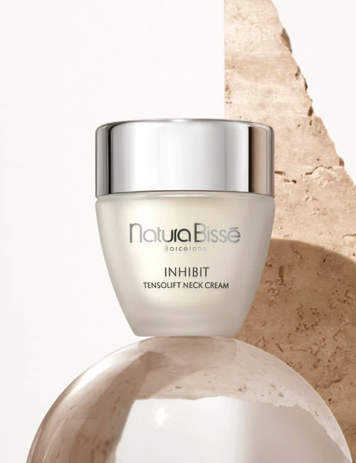 Natura Bissé's Inhibit Tensolift Neck Cream in an elegant packaging placed on top of a glass ball.